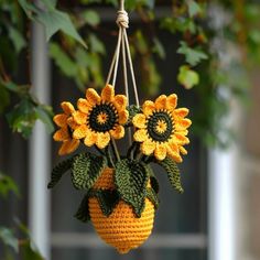 a crocheted sunflower hanging from a string with green leaves and yellow flowers