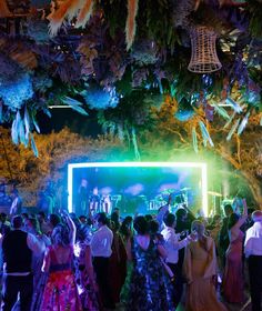 a large group of people standing around in front of a stage with lights on it