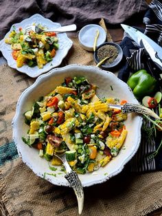 a bowl filled with salad next to two forks and spoons on top of a table