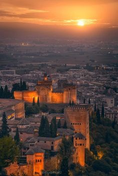 the sun is setting over an old city and its castle like structures are lit up