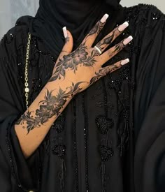 a woman with tattoos on her arms and hands is wearing a black dress, holding a gold chain