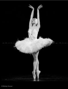 a ballerina in white tutu with her arms outstretched