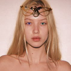 a woman with long blonde hair and blue eyes is wearing a head piece made out of chains