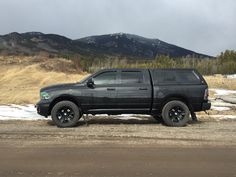 a black truck parked on the side of a road in front of snow covered mountains