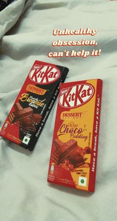 two chocolate bars sitting on top of a bed next to an advertisement for kitkat