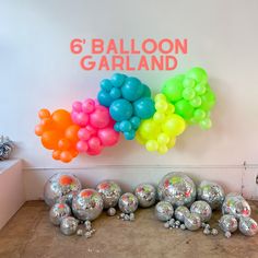 balloons are lined up on the floor in front of a sign that reads 6 balloon garland