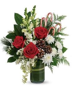 a christmas bouquet with red roses, white flowers and candy canes in a green vase