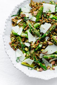 a white bowl filled with asparagus and other vegetables on top of a table