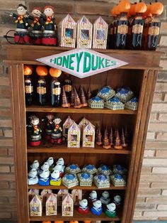 a shelf filled with lots of different types of candy on top of wooden shelves next to a brick wall