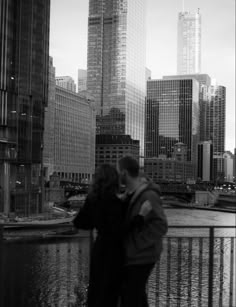 a man and woman standing next to each other in front of tall buildings