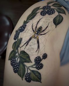 a woman's thigh with a spider and berries tattoo on it