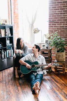 a man and woman sitting on the floor playing guitar