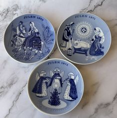 three blue and white plates sitting on top of a marble counter next to each other