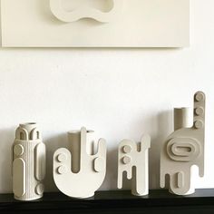 three white vases sitting on top of a black shelf