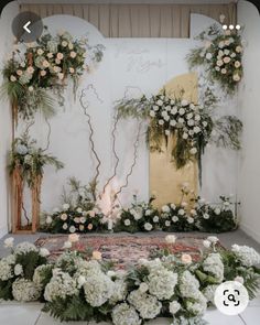 a wedding ceremony setup with flowers and greenery on the floor in front of an arch