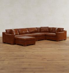 a large brown leather sectional sofa sitting on top of a hard wood floored floor