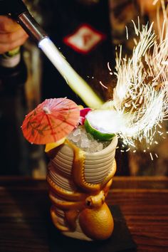 someone is holding an umbrella over a small vase filled with ice and fruit on a table