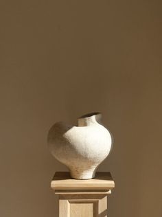 a white vase sitting on top of a wooden stand