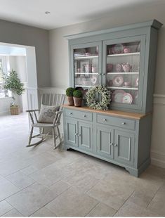 a gray china cabinet with pink and white plates on it's glass front doors