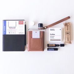 an assortment of personal items laid out on a white surface, including a leather case