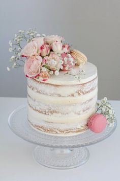 a white cake with pink flowers on top sitting on a glass platter next to an egg