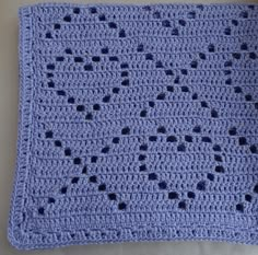 a blue crocheted dishcloth is laying on a white table cloth with holes in it