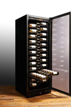 a wine cooler with many bottles of wine in it on a wooden floor next to a wall