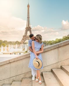 a man and woman standing next to each other in front of the eiffel tower