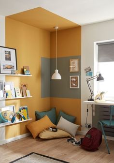 a room with yellow and green walls, bookshelves and various pictures on the wall