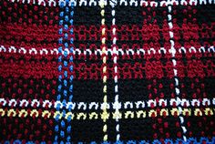 a close up view of a knitted blanket with multicolored squares on it