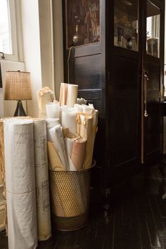 several rolls of toilet paper are stacked in a metal trash can next to a black cabinet