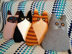 four knitted cats sitting on top of a couch next to each other in different colors