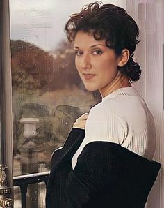 a woman leaning against a window with her arms crossed