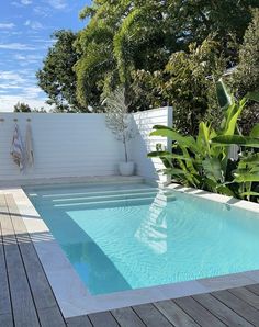 an empty swimming pool in the middle of a wooden decked area next to a white fence