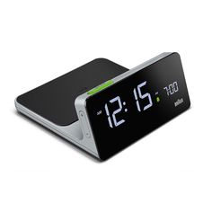 the alarm clock is black and white with green numbers on its display, as well as an extra battery