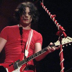 a man in red shirt playing an electric guitar