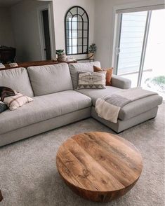 a living room filled with furniture and a wooden table in front of a large window