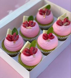 cupcakes with pink frosting and raspberries in a box