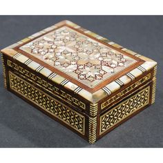 an ornately decorated wooden box sitting on top of a black surface with gold trimmings