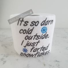 a white cup with black writing on it sitting on top of a marble counter next to a sign that says it's so damn cold outside i just tarted snowflakes