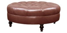 a brown leather ottoman sitting on top of a wooden table