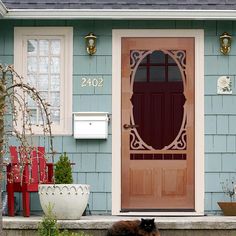 a black cat laying on the steps in front of a house with a red door