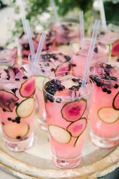 there are many glasses with drinks in them on the tray and one is filled with watermelon