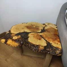 a table made out of tree trunks on top of a wooden floor next to a gray couch