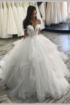 a woman in a white wedding dress standing next to some dresses