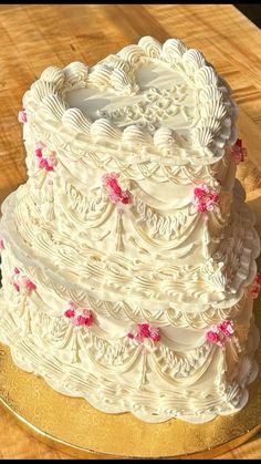 a white wedding cake with pink flowers on the top is sitting on a wooden table