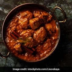 a pan filled with meat and spices on top of a table