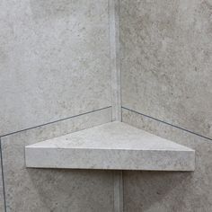 the corner of a shower stall with marble walls and flooring in an empty room