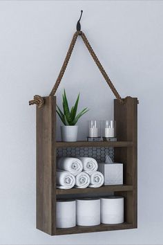 a shelf with towels, candles and plants hanging from it's sides on the wall