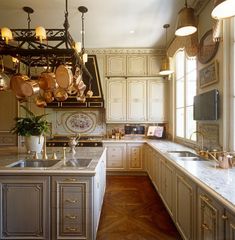 a large kitchen with white cabinets and marble counter tops, gold accents on the ceiling